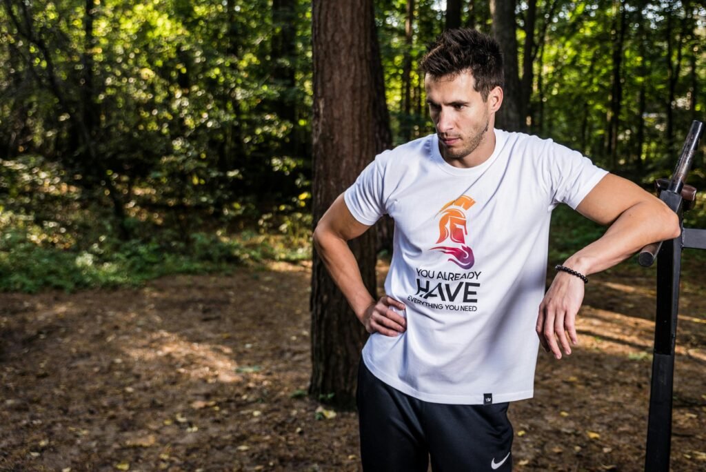 Man in forest wearing casual t-shirt, resting during outdoor workout.